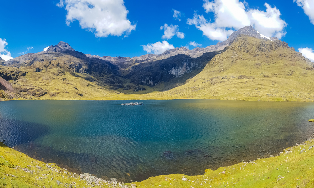 alt="Lares trek hike in the Andes mountains with large blue lake surrounded by mountains in Peru"