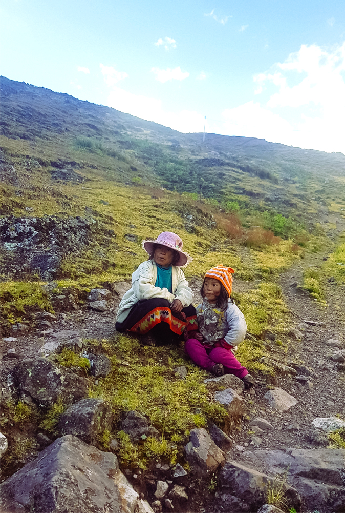 alt="Local Quechuan children sitting on the floor on the mountains in Peru"