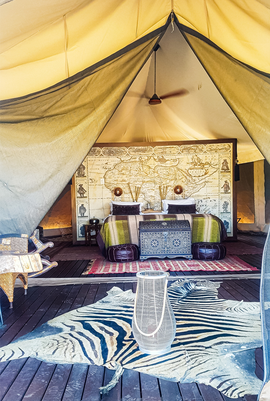 alt="Kuganha tented safari with zebra rug and atlas wall behind bed at Inverdoorn Gamer Reserve blog post"
