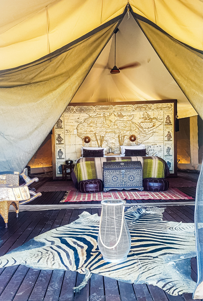 alt="Kuganha tented safari with zebra rug and atlas wall behind bed at Inverdoorn Gamer Reserve"