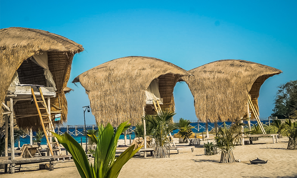 alt="Le Pirate Island private island beach huts in a row with straw roof and with sea view"