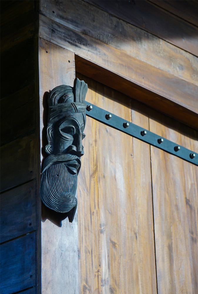 alt=“Kandy cabana wall decoration of a face mask and studded door”