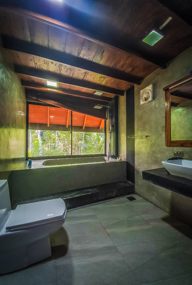 alt=“Kandy cabana view of the toilet with concrete effect walls and timber ceiling”