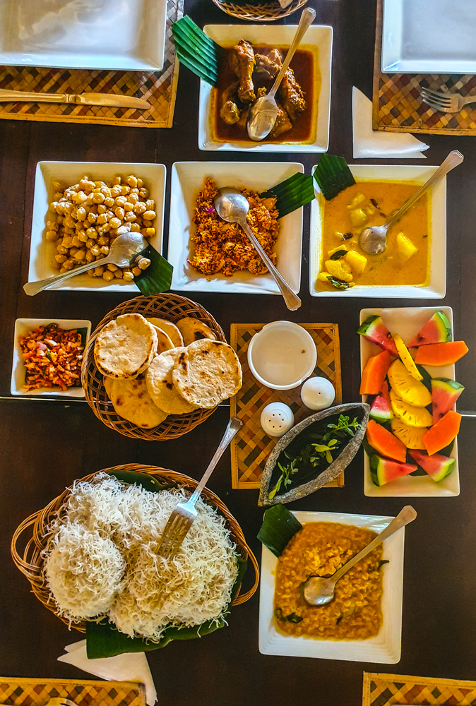 alt=“Kandy cabana Sri Lankan breakfast with curry, naan, fruit, string hoppers, and chickpeas”