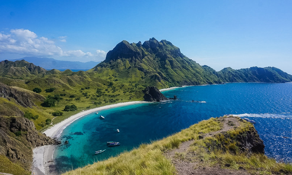 alt="Beautiful right view of Padar Island in Indonesia showing mountains with beach and sea"